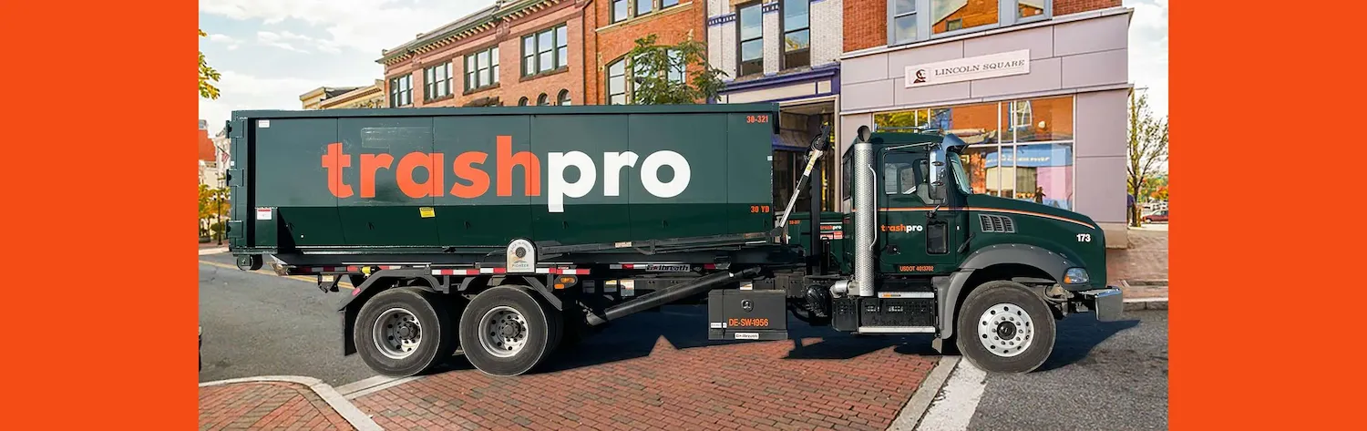 Green TrashPro truck with a dumpster in an urban city street environment with a bright orange background